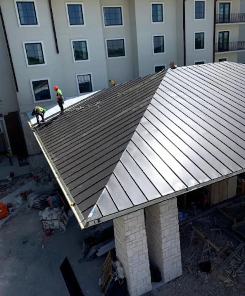 Crew installing standing seam metal roof panels on a commercial project in Dent
